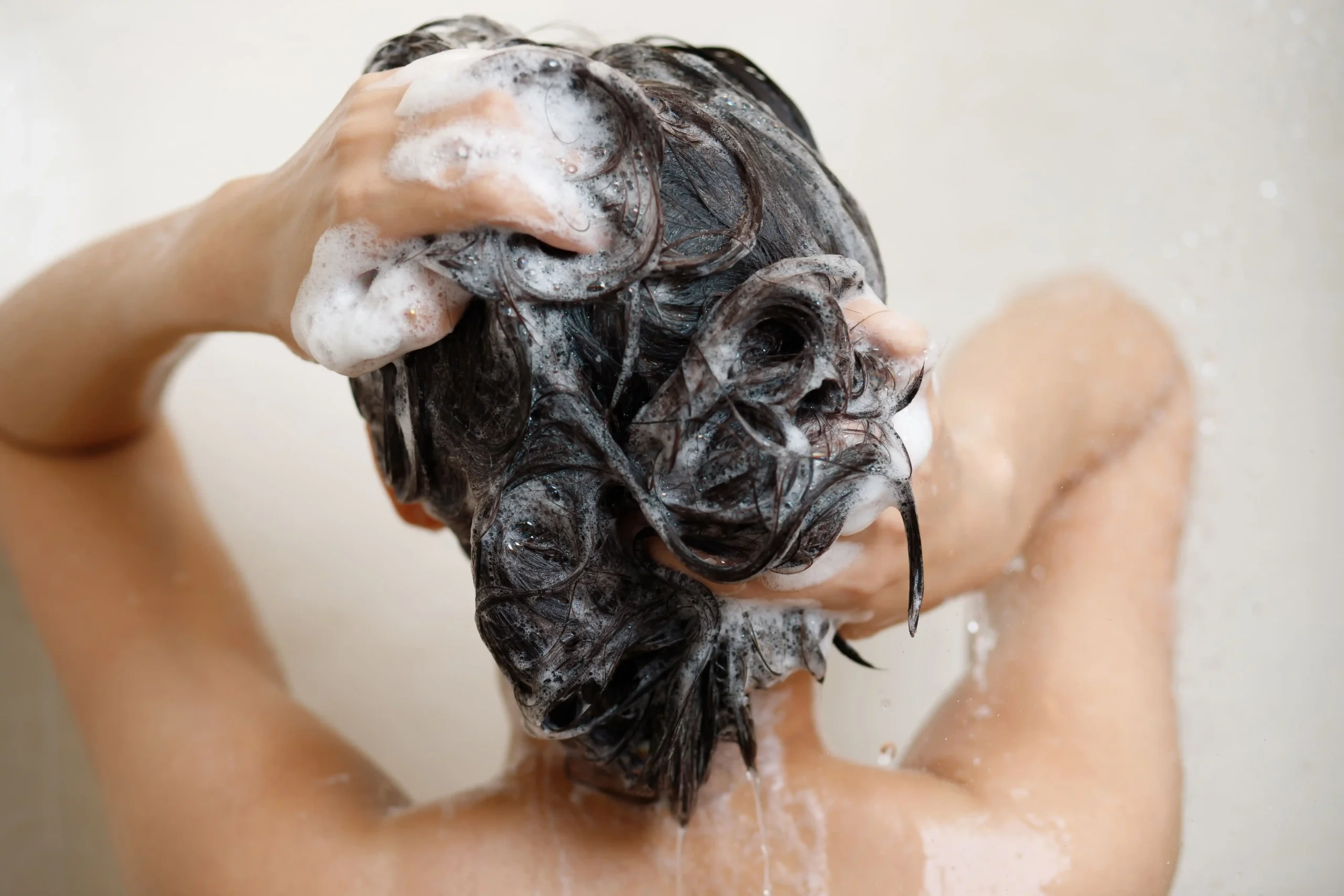 A woman washing hair with shampoo