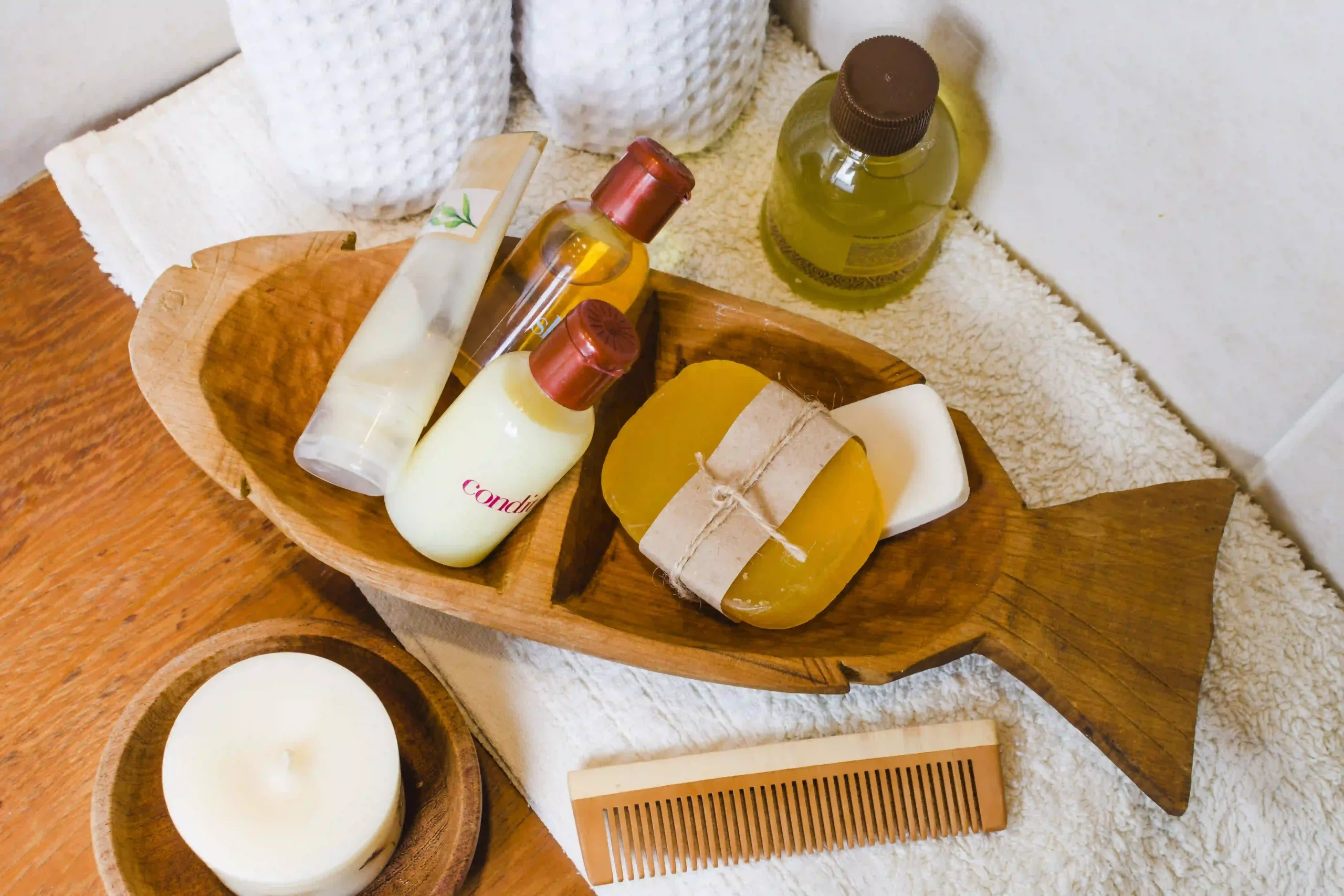 Variety of hair care products including oils, soaps, and a wooden comb in a fish-shaped tray.