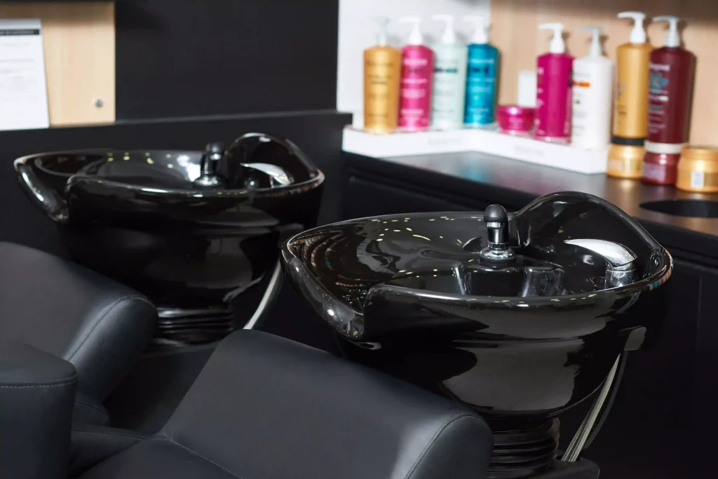 Clean, modern black ceramic hair washing sinks and professional hair care products at a salon station.