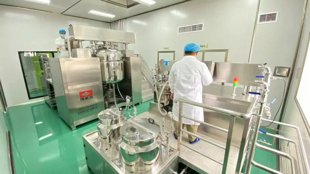 Workers in protective gear operating a large-scale industrial emulsification and mixing station in a cleanroom.