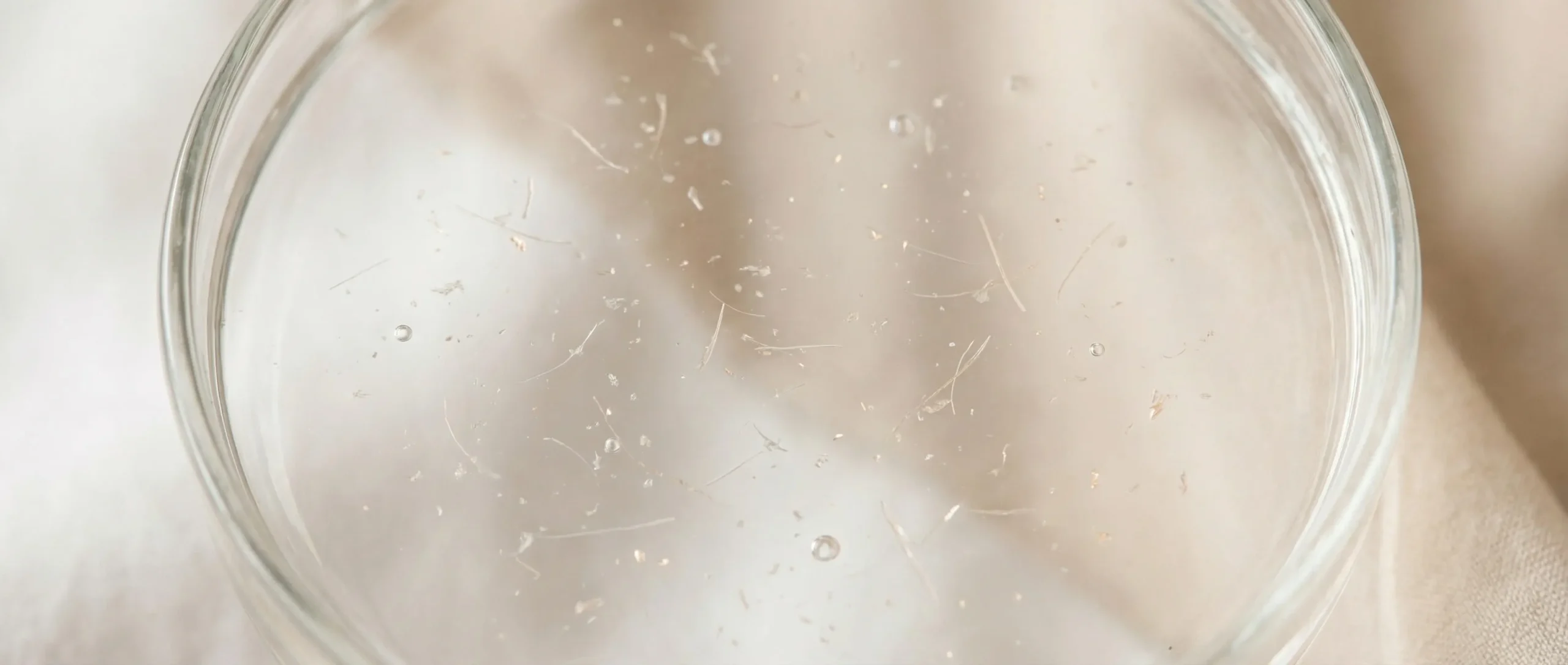 Macro shot of pure hydrolyzed keratin particles in a clear solution, showcasing advanced hair repair ingredients.