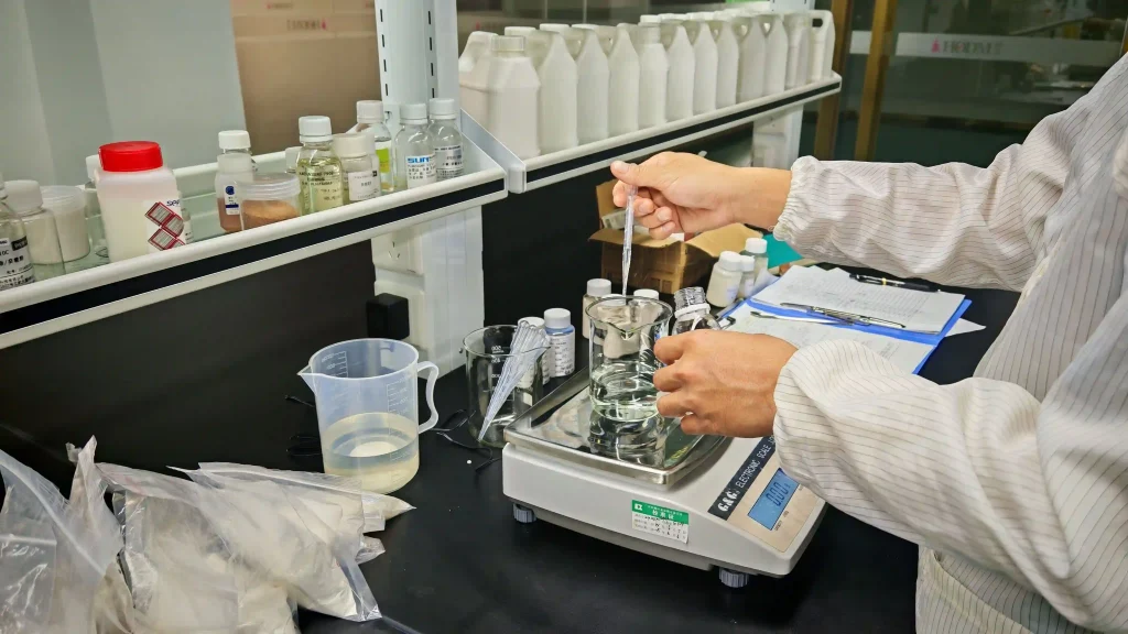 A technician using a pipette to precisely add liquid reagents into a beaker on a digital analytical scale.