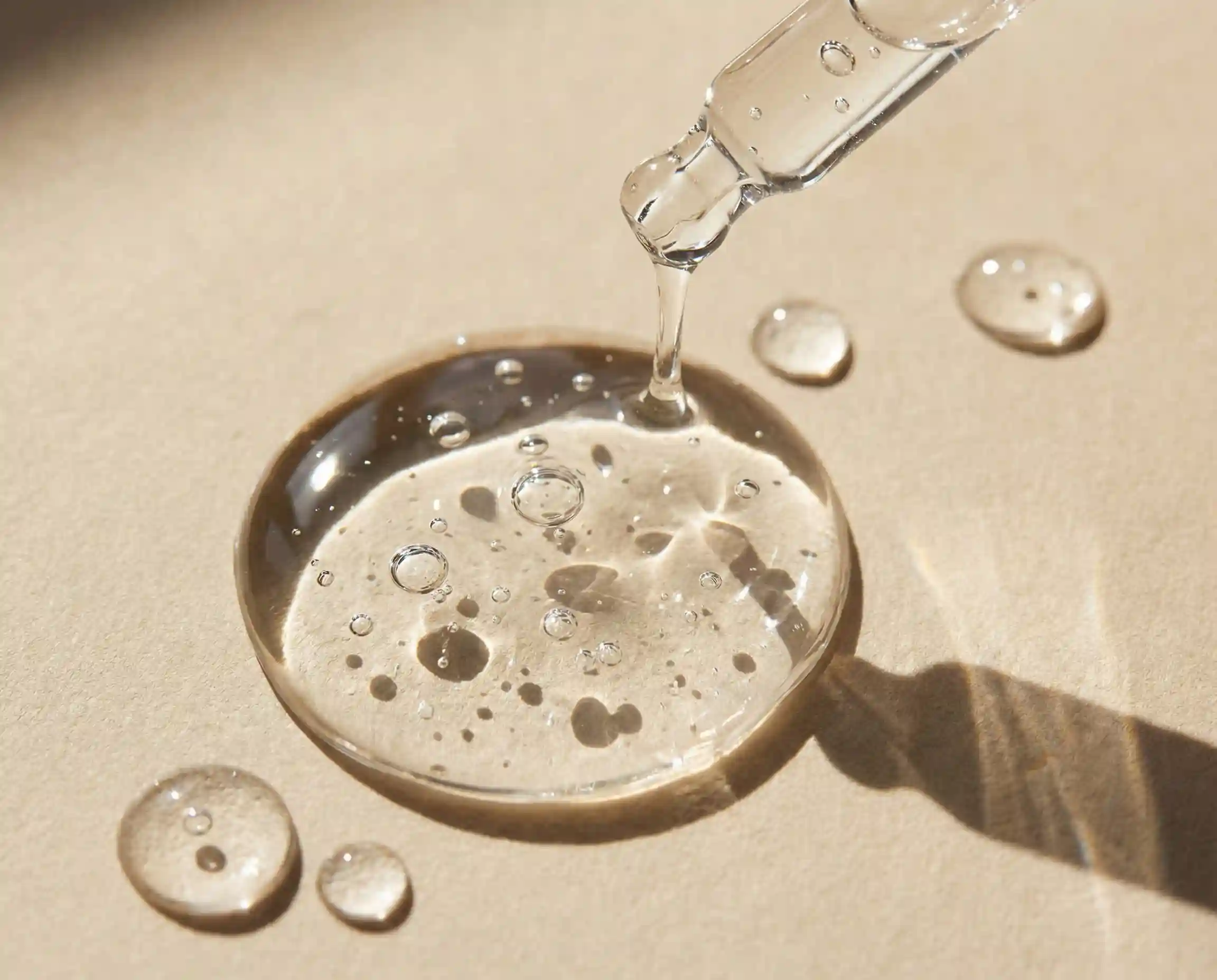 Viscous serum droplet falling from a pipette, symbolizing high-purity hair care active ingredients.