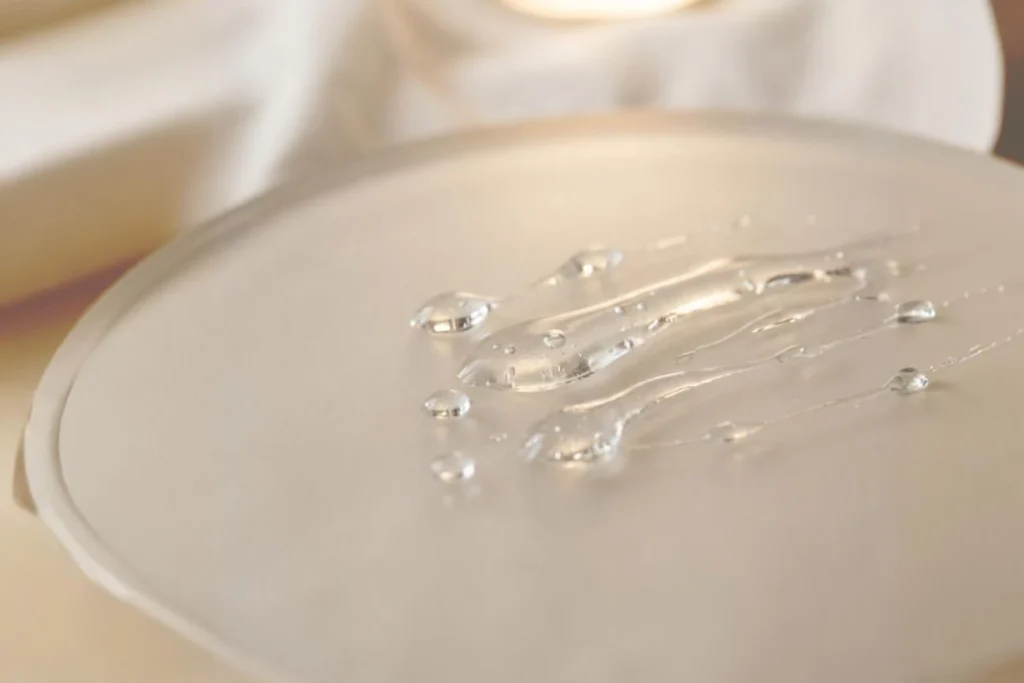 Macro shot of clear Glyoxylic Acid liquid on a frosted glass surface, a key ingredient for semi-permanent hair straightening.