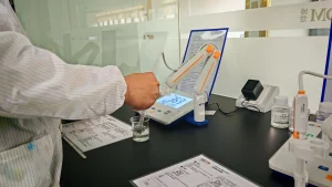 Close-up of a laboratory technician using a digital pH meter to test a water sample in a beaker.