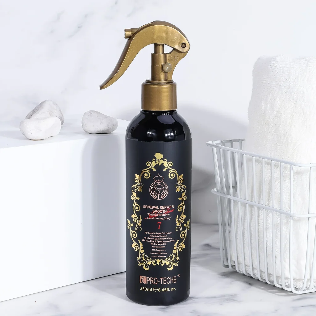 A 250ml black bottle of "Renewal Keratin Smooth Thermal Protector Conditioning Spray 7" featuring an ornate gold label and a gold trigger spray nozzle, placed on a marble surface next to a white towel basket.
