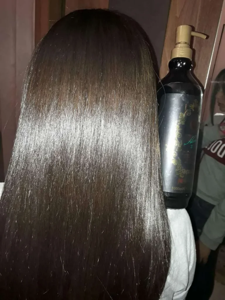 Back view of a person with long, straight, glossy brown hair; a pump-style hair product bottle sits nearby on the right.