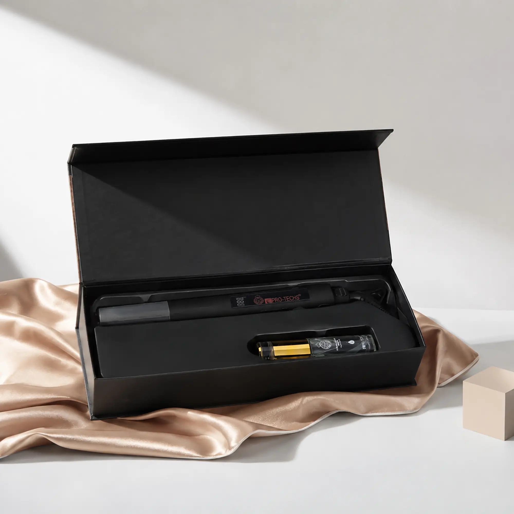 Open black presentation box with a cylindrical gadget inside, resting on beige satin fabric.