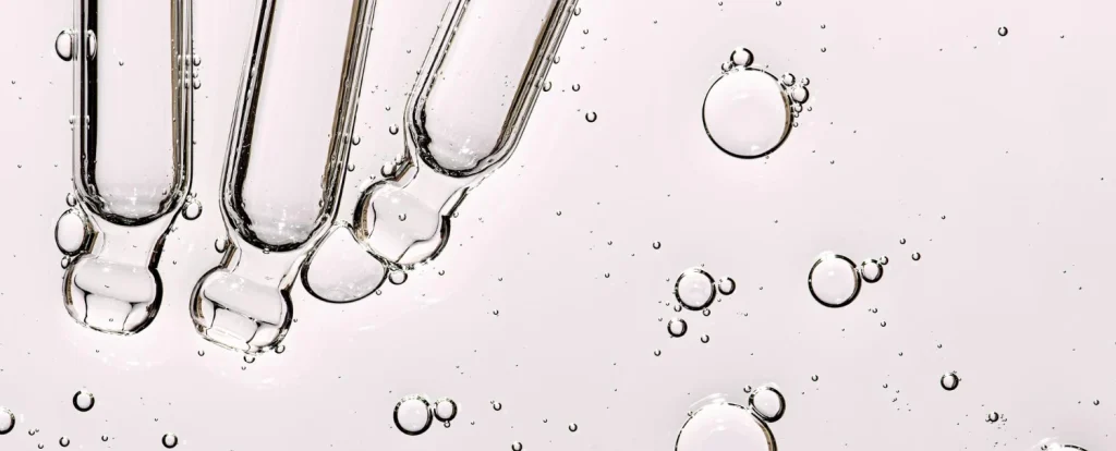 Close-up of active cosmetic ingredients with glass droppers, showcasing custom keratin and hair serum formulation