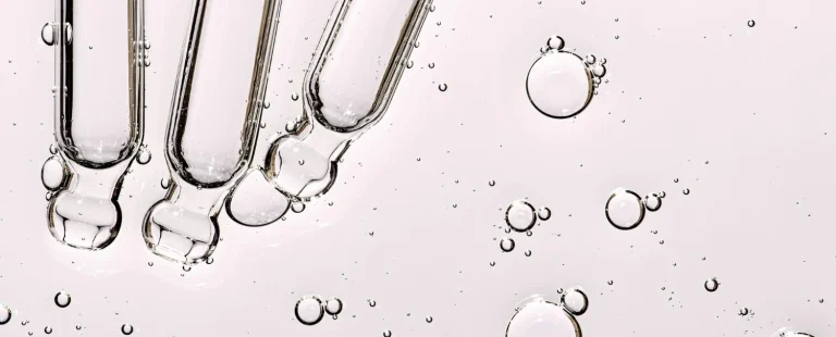 Close-up of active cosmetic ingredients with glass droppers, showcasing custom keratin and hair serum formulation