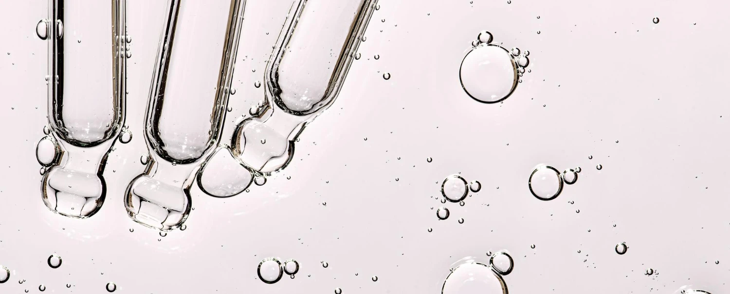 Close-up of active cosmetic ingredients with glass droppers, showcasing custom keratin and hair serum formulation