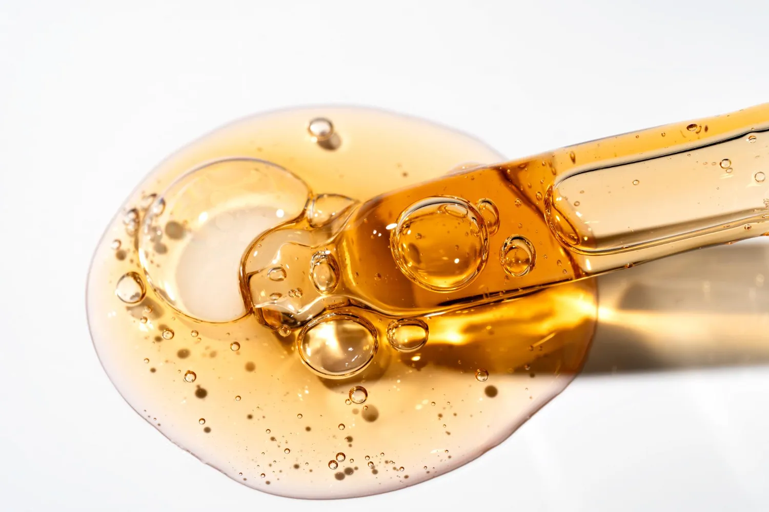 Macro shot of golden argan hair oil droplet with a glass pipette