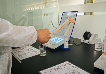 Close-up of a laboratory technician using a digital pH meter to test a water sample in a beaker.